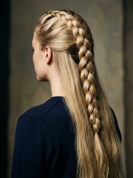 A side view of a blonde woman wearing a French braid that pulls hair back from her forehead.