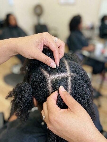 Close-up of a stylist dividing textured hair into clean, square sections for braiding.