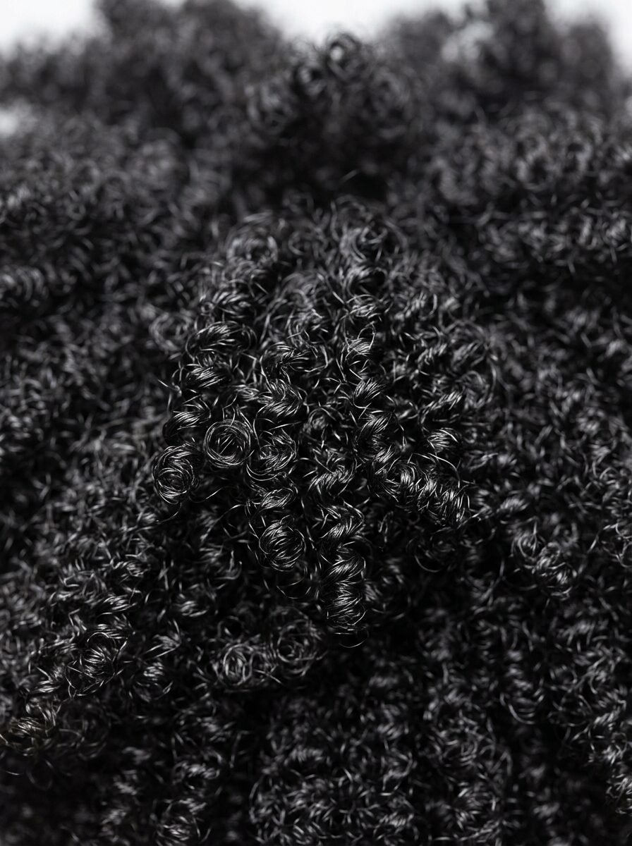 A detailed macro view of dense, spiral black hair curls filling the frame.