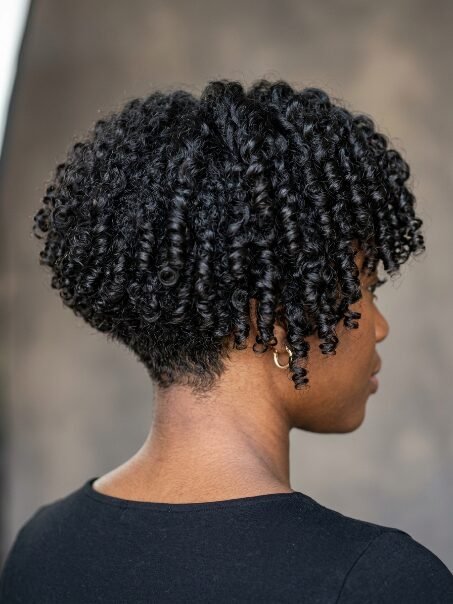 Close up of a woman showing her short, tapered hairstyle with bouncy, defined black curls.