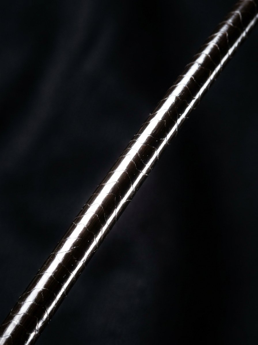 Close up of a cylindrical object with a shiny, dark brown snake-skin pattern wrapped around it.